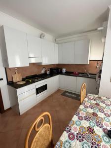 eine Küche mit weißen Schränken und einem Tisch und Stühlen in der Unterkunft Orchidea Apartment Lecco in Lecco