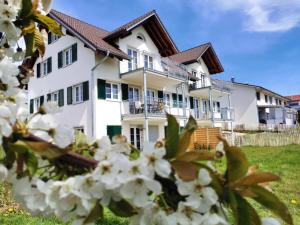 uma casa branca com flores brancas à frente em Landhaus Vogel - helle und lichtdurchflutete Maisonette-Ferienwohnung em Wasserburg