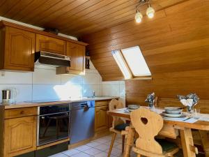 una cocina con armarios de madera y una mesa con sillas. en Ferienwohnung Blumenoase - gemütliche Ferienwohnung zwischen Allgäu und Bodensee, en Sigmarszell