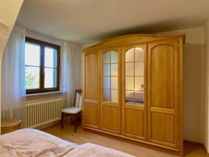 1 dormitorio con armario de madera y ventana en Ferienwohnung Blumenoase - gemütliche Ferienwohnung zwischen Allgäu und Bodensee, en Sigmarszell