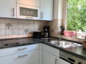 een keuken met witte kasten, een wastafel en een raam bij Ferienwohnung Seebrise in Wasserburg