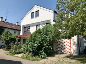 een wit huis met een rode en witte muur bij Ferienwohnung Seebrise in Wasserburg