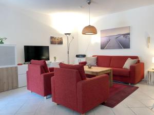 a living room with two red chairs and a tv at Ferienwohnung Fischerpromenade in Kressbronn am Bodensee