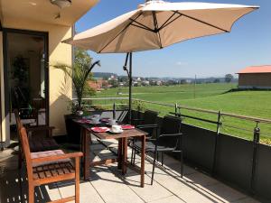 a table and chairs with an umbrella on a balcony at Ferienwohnung Seetraum - Hoch über dem See, großzügig mit großem Balkon in Kressbronn am Bodensee