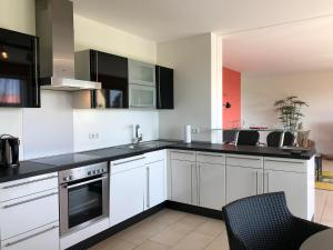 a kitchen with white cabinets and black counter tops at Ferienwohnung Seetraum - Hoch über dem See, großzügig mit großem Balkon in Kressbronn am Bodensee +16 photos