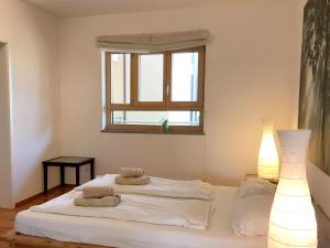 a white bedroom with two towels on a bed at Ferienwohnung Seetraum - Hoch über dem See, großzügig mit großem Balkon in Kressbronn am Bodensee