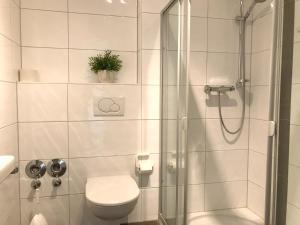 a white bathroom with a shower and a toilet at Ferienwohnung Seetraum - Hoch über dem See, großzügig mit großem Balkon in Kressbronn am Bodensee