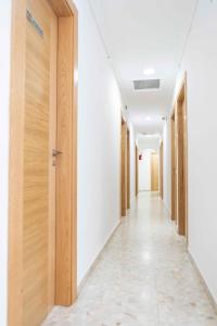 un corridoio vuoto di un edificio adibito a uffici con porte in legno di Pensión Dos Hermanas a Bolaños de Calatrava