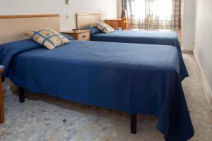 two beds with blue sheets in a room at Pensión Dos Hermanas in Bolaños de Calatrava