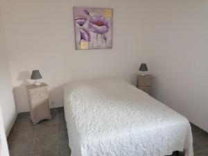 a bedroom with a white bed and two night stands at Gîte M in Codognan