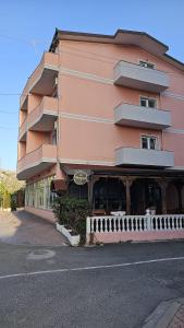 um edifício cor-de-rosa ao lado de uma rua em Hotel Marigona em Shëngjin