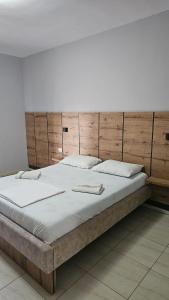 um quarto com uma cama grande e uma cabeceira em madeira em Hotel Marigona em Shëngjin