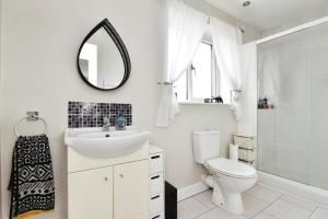 a bathroom with a toilet and a sink and a mirror at 3 Bed Home for Contractors & Relocators with Parking, Garden & WiFi 30 mins to Alton Towers in Stoke on Trent
