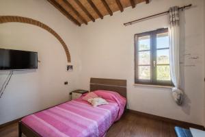 um quarto com uma cama rosa e uma janela em Podere Palazzetto em Buonconvento