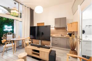 eine Küche und ein Wohnzimmer mit einem großen Flachbild-TV in der Unterkunft Secret Jungle Bordeaux Chartrons - Hyper-Centre Jacuzzi Bain Balnéo & Home cinéma in Bordeaux + 10 Fotos