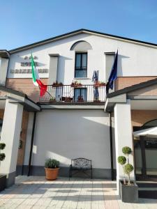 - un bâtiment blanc avec deux drapeaux sur un balcon dans l'établissement BRIXELLUM, à Brescello