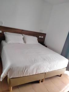 Bett mit weißer Bettwäsche und einem Kopfteil aus Holz in der Unterkunft BRIXELLUM in Brescello