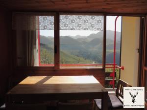 ein Esszimmer mit einem Tisch und einem großen Fenster in der Unterkunft Stag Apartment in Prato Nevoso