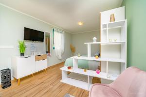 a living room with white shelves and a pink chair at Studio Leon & rent a quad in Mali Lošinj
