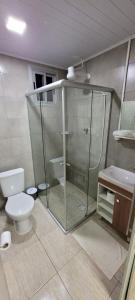 uma casa de banho com uma cabina de duche em vidro e um WC. em Pousada Ritter em Bento Gonçalves