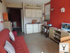 eine Küche mit roten Wänden und einem roten Sofa in einem Zimmer in der Unterkunft Stag Apartment in Prato Nevoso