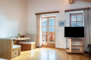 a living room with a flat screen tv and a desk at Funtnatsch Apartment Schlern in Laion
