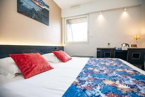 Un dormitorio con una cama con almohadas rojas. en Hôtel de France, en Camaret-sur-Mer