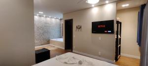 a bathroom with a bed and a tv on the wall at Pousada Banana Cipó in Serra do Cipo