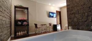 a bathroom with a tub and some chairs and a table at Pousada Banana Cipó in Serra do Cipo