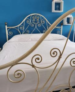 un letto di metallo con lenzuola bianche e una parete blu di Residence Torre Giuseppina a Napoli