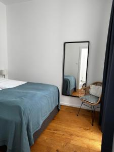 DOWA Apartments Thaliastrasse في فيينا: غرفة نوم بسرير ومرآة وكرسي