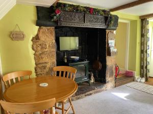 a dining room with a table and a fireplace at Lemon Cottage in Hatherleigh