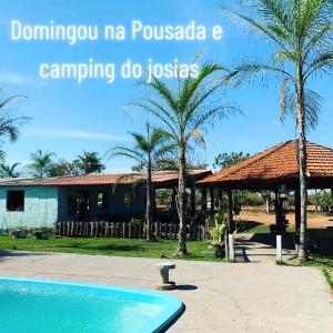 un complejo con piscina y palmeras en pousada camping do josias, en Nobres