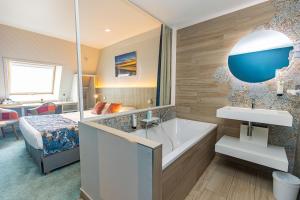 a bathroom with a tub and a bedroom with a bed at Logis Hôtel de France - Face à la Mer in Camaret-sur-Mer