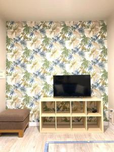a living room with a tv on a wall with a palm tree wallpaper at El Alma de Granada 2 in Granada