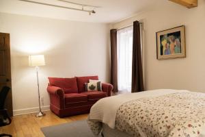 1 dormitorio con 1 cama y 1 silla roja en Royal Dalhousie, en Quebec