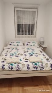 a white bed with a floral bedspread on it at Apartmani Elix in Banja Luka