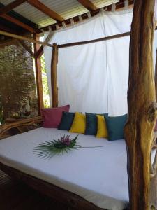 un sofá blanco con almohadas coloridas en el porche en Bungalow atypique Ti Bambou à 500m de la plage en Sainte-Anne