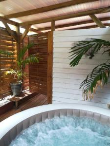 a hot tub on a patio with a pergola at Bungalow atypique Ti Bambou à 500m de la plage in Sainte-Anne