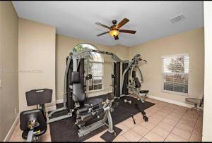 een fitnessruimte met loopbanden en een plafondventilator bij Luxurious Farm Style House in Kissimmee
