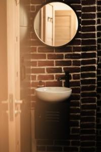 a bathroom with a sink and a mirror on a brick wall at Studio Zeus in Neptun