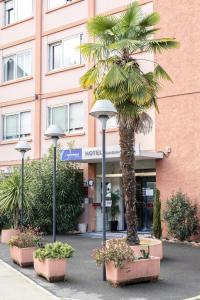 a palm tree in front of a hotel at The Originals City, Hôtel Rive Droite, Albi "Quartier Madeleine" in Albi