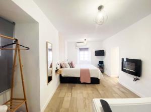 een witte slaapkamer met een bed en een televisie bij Amores Loft Rural in Alcalá de los Gazules