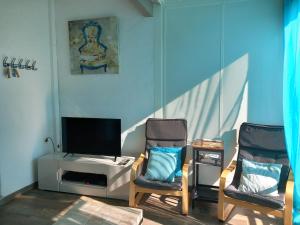 ein Wohnzimmer mit 2 Stühlen und einem TV in der Unterkunft LA MAISON DU LAC climatisée et WiFi gd F3 in Port-la-Nouvelle