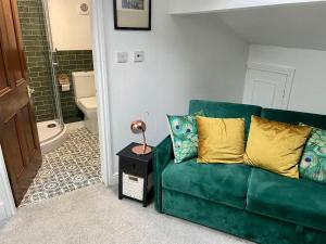 a living room with a green couch and a bathroom at No 11 Rooms in Haworth