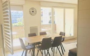 a dining room with a table and chairs and a clock at Le palais Omnisport grand apt avec terrasse by Weekome in Marseille