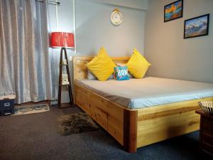 een slaapkamer met een houten bed met gele kussens bij The Sunset Nest offbeat Homestay in Darjeeling +78 foto's