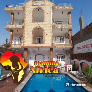 a villa with a swimming pool in front of a building at Mama Africa Apts & Studios in Luxor