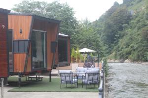 a house with a table and chairs next to a river at Akasya Tiny House in Ardeşen