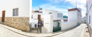 een steegje met witte gebouwen en een stenen muur bij Amores Loft Rural in Alcalá de los Gazules